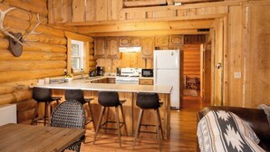 Ein Holzblockhaus mit Küche, Essbereich und Wohnzimmer.