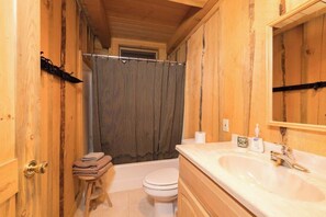Une salle de bain en bois avec une baignoire, des toilettes et un lavabo.