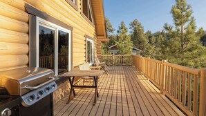 Eine Holzterrasse mit Grill und Gartenmöbeln.