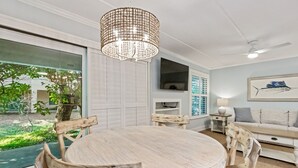 Un espace repas comprenant une table ronde et des chaises, un luminaire suspendu et une vue sur l’extérieur.