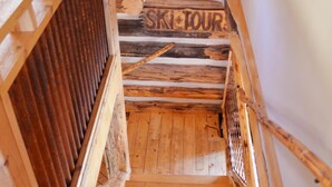Eine Holztreppe mit einem Schild, auf dem 'SKI TOUR' steht, die zu einer höheren Ebene führt.