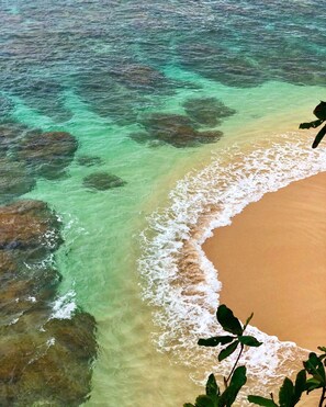 Una spiaggia con acque turchesi trasparenti, una riva sabbiosa e rocce visibili.