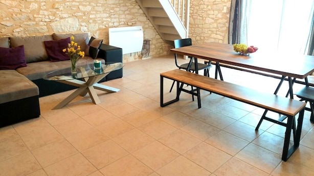 A living room with a stone wall, a sofa, a glass coffee table, a wooden bench, and a staircase. - La Borieta (Labastide-de-Penne)