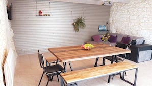 A dining area with a wooden table, black chairs, and a bench. There is a sofa with cushions and a potted plant on the wall. - La Borieta (Labastide-de-Penne)