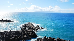 Vista costera con terreno rocoso y mar azul cristalino.