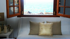 Un dormitorio con vista al océano a trav és de una ventana con contraventanas de madera.