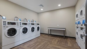 Une buanderie équipée de plusieurs machines à laver et de plusieurs sèche-linge, avec une table et un plancher en bois.