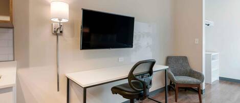 Un espacio de oficina moderno con escritorio, silla y televisor montado.