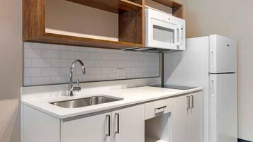 A kitchen with a stainless steel sink, a microwave, and a refrigerator.