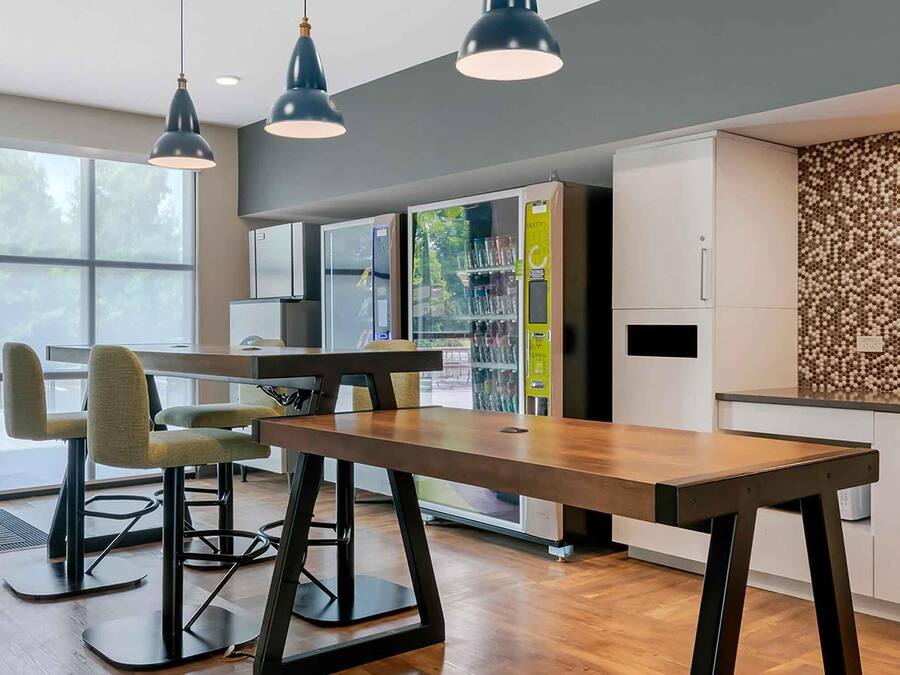 Una cocina moderna con una mesa de madera, taburetes de bar, lámparas colgantes y un salpicadero con diseño de panal.