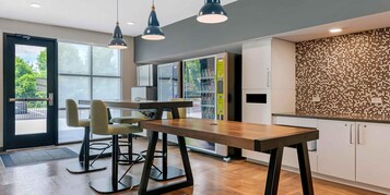 Una cocina moderna con una mesa de madera, taburetes de bar, lámparas colgantes y un salpicadero con diseño de panal.