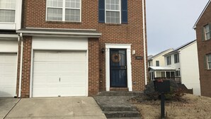 A two-story brick building with a white garage door, a front door with a wreath, and a mailbox. - Comfy Blue Studio with Great Amenities (Washington)