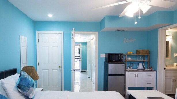 A bedroom with a bed, a desk, and a kitchenette. - Comfy Blue Studio with Great Amenities (Washington)