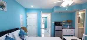 Un dormitorio con cama, escritorio y kitchenette.