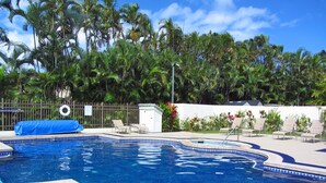 Una piscina con lettini e un piccolo giardino.