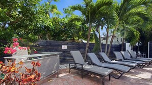 A patio area with lounge chairs, a small table, and a decorative plant. - Total Oasis - 8BR Resort Compound, Pool & Tiki Bar, Sleeps 30, Near Cruise Port (Hollywood)