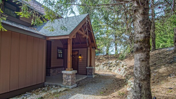A wooden cabin with a stone entrance, surrounded by trees and a gravel path. - Tree Top 19, Snowpeak 2 Bedroom Spectacular Townhome Slope Side (Snowshoe)