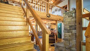 Un escalier en bois mène à une mezzanine où se trouve une cheminée en pierre.