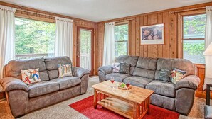 Ein gemütliches Wohnzimmer mit zwei grauen Sofas, einem Holztisch und einem roten Teppich.