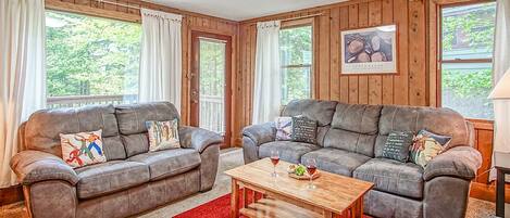 A cozy living room with two grey sofas, a wooden coffee table, and a red rug.
