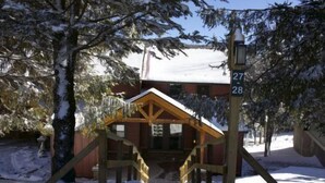 Eine Holzhütte mit schneebedecktem Dach und einer Holztreppe zum Eingang.