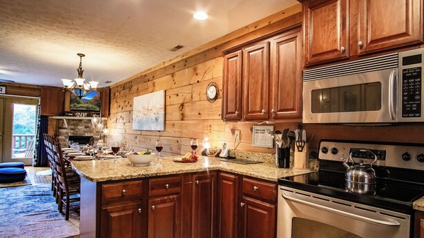 A kitchen with wooden cabinets, a microwave, an oven, and a dining area with a table set for four.