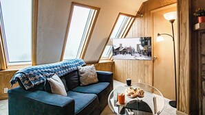 Une pièce chaleureuse avec un canapé, une table ronde en verre et une photo encadrée accrochée au mur.