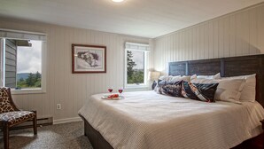 A bedroom with a large bed, two windows, a framed picture, and a chair. - Powderidge 40: Slope Side, Sleeps 9 Full Kitchen (Snowshoe)