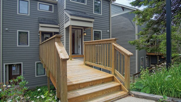 A multi-story residential building with a wooden staircase leading to a front door. - Powderidge 40: Slope Side, Sleeps 9 Full Kitchen (Snowshoe)