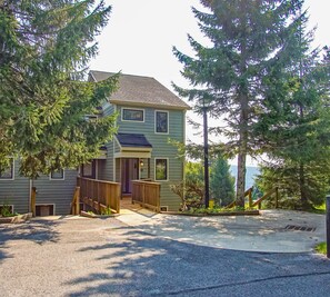 A two-story house with a front porch, a driveway, and a playground area.