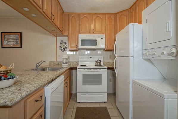 A kitchen with wooden cabinets, a microwave, a stove, a dishwasher, and a refrigerator. - Leatherbark - 202A 2 BR Condo Spacious Living Room (Snowshoe)