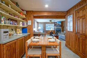 Cozy cabin-style accommodation with a dining table for four, kitchen area, and fireplace.