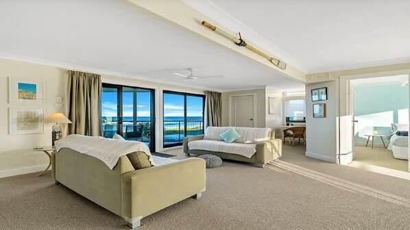 A hotel room with two sofas, a dining area, and a balcony with a view.