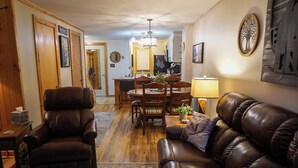 A cozy living room with a leather sofa, a leather armchair, and a dining area with a table and chairs.