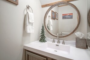 A bathroom with a white sink, a mirror with a wooden frame, and a small Christmas tree decoration.