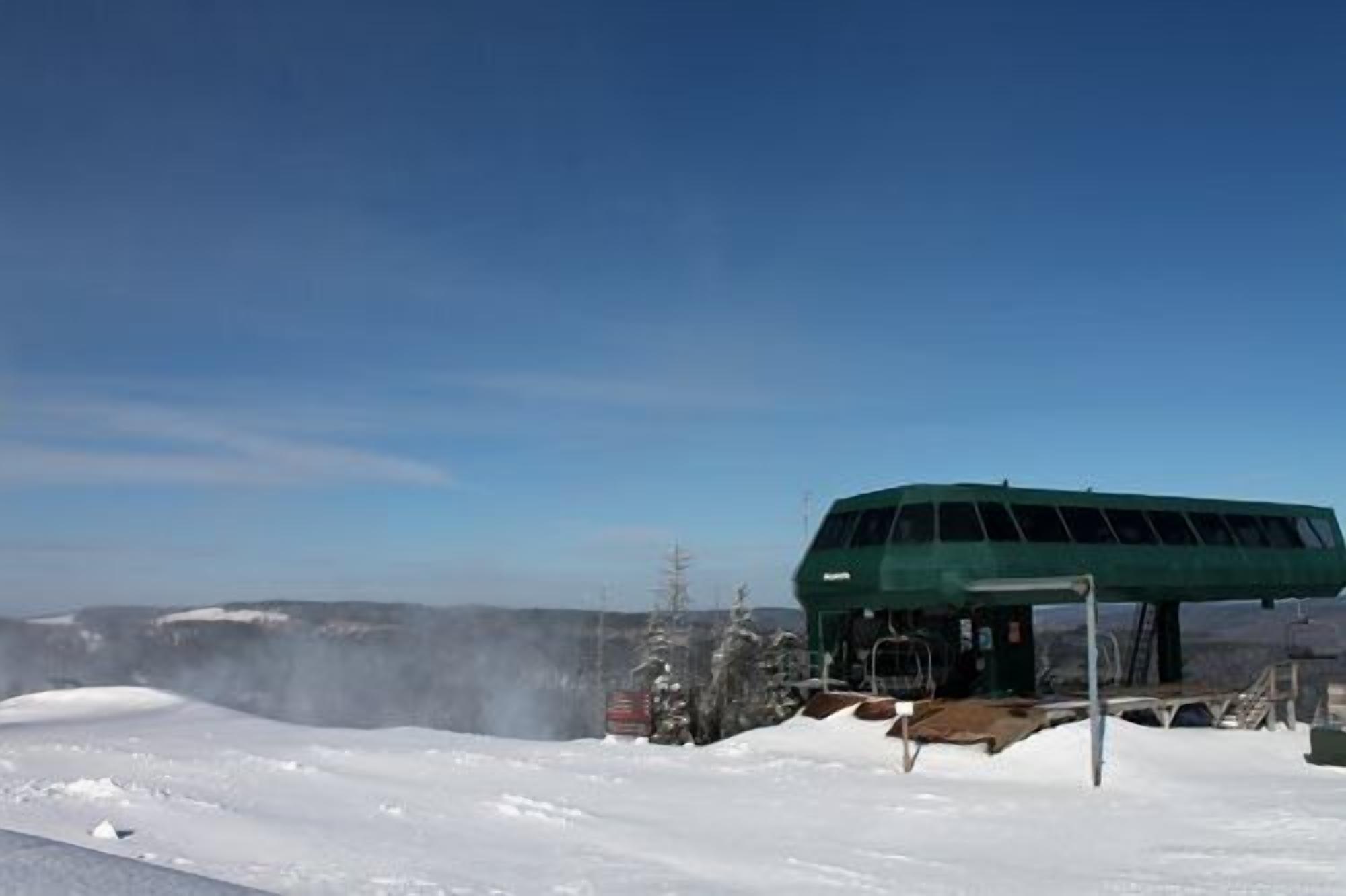 A snow-covered landscape with a green building, possibly a lodge or facility, in the background.