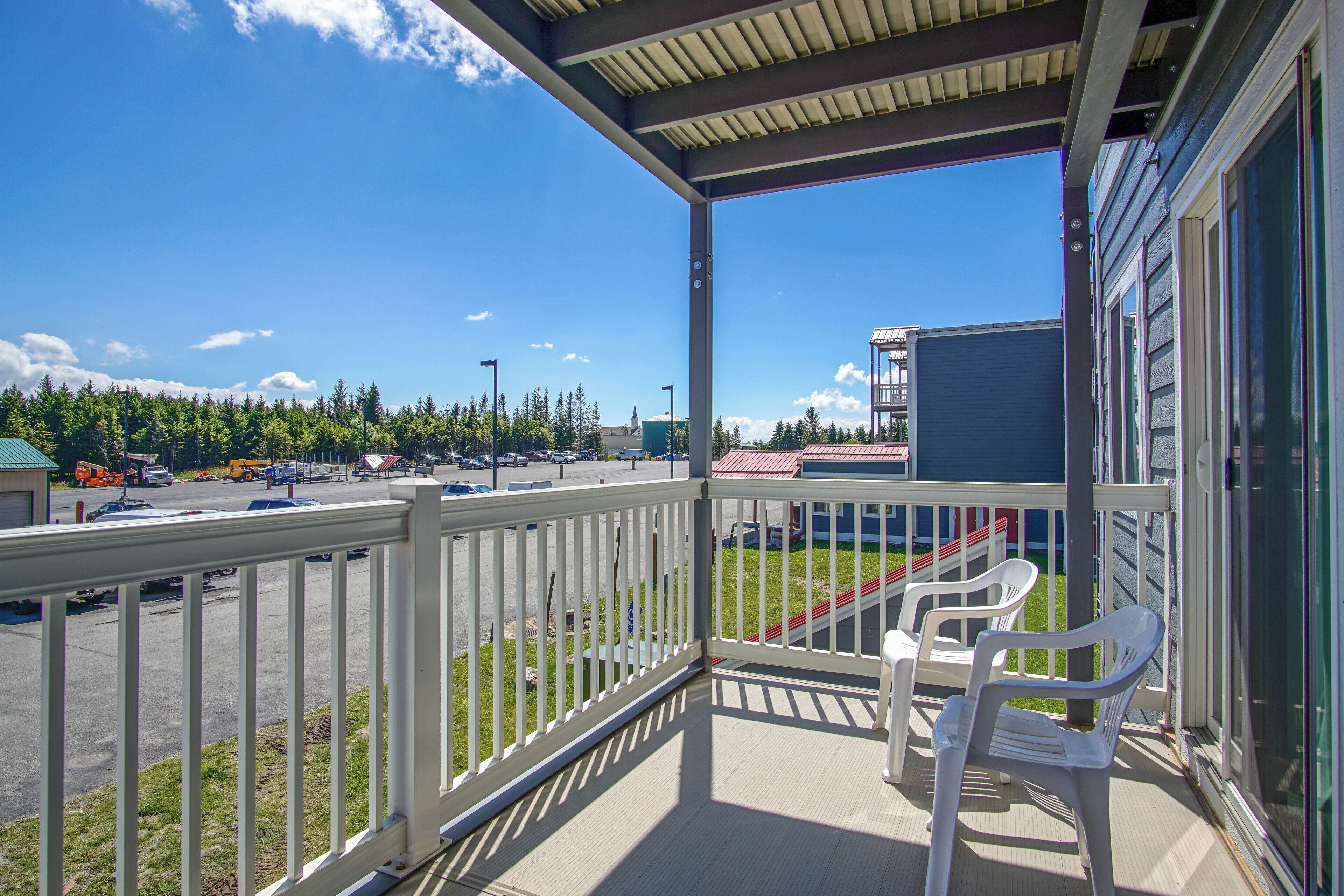 A balcony with a view of a parking lot and a building in the background.