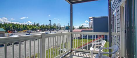 A balcony with a view of a parking lot and a building in the background.