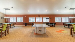 A billiards room with a pool table, several chairs, and windows with blinds. - Pinetop | Couples Mountain Retreat | Pool + Hot Tub (Pinetop)