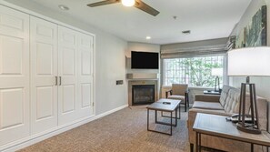 A living room with a fireplace, a sofa, a coffee table, and a TV mounted on the wall.