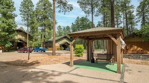 A lodge with a covered seating area, a small building with a porch, and a parking lot with cars.
