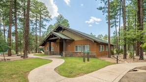A lodge with a stone foundation, wooden exterior, and a curved driveway.