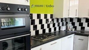 Une cuisine moderne avec un dosseret à carreaux noirs et blancs, des appareils en acier inoxydable et un panneau jaune au-dessus du comptoir.