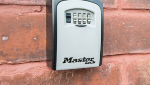 Un cadenas de la marque Master Lock fixé à un mur de briques.
