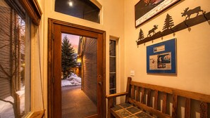 A wooden door leading to a snowy outdoor area, a bench, and a wall with a sign and a framed picture. - 4BD Home  Private Hot Tub  Minutes to Slopes & Main St (Park City)