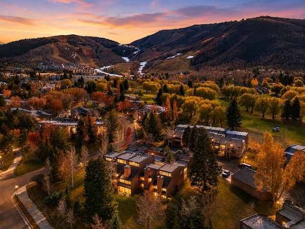 A residential area with modern houses, a river, and surrounding hills.