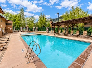Une piscine avec des chaises longues, une pergola et un mur en pierre.