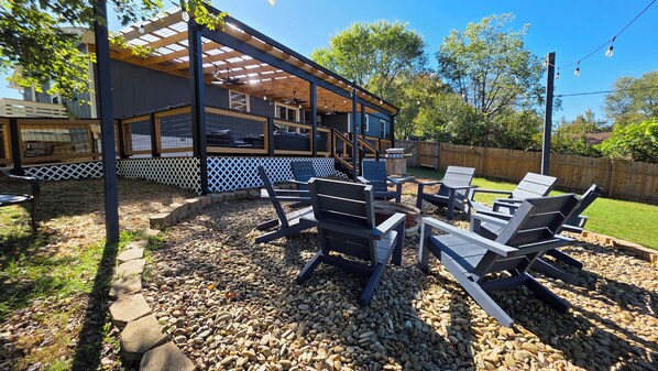 An outdoor patio with a pergola, seating area, and a view of a building with a lattice fence.