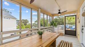 Un espace extérieur abrité, doté d’une terrasse en bois, d’un ventilateur de plafond et offrant une vue sur les maisons voisines.