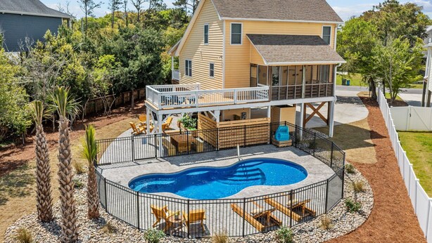 Une maison à deux étages avec une piscine, une terrasse et du mobilier de jardin à l’arrière.